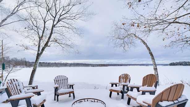 A snow-covered outdoor seating area with Adirondack chairs and a circular fire pit. - Lake Access w/ Dock! Hayward Cabin Hideaway (Hayward)
