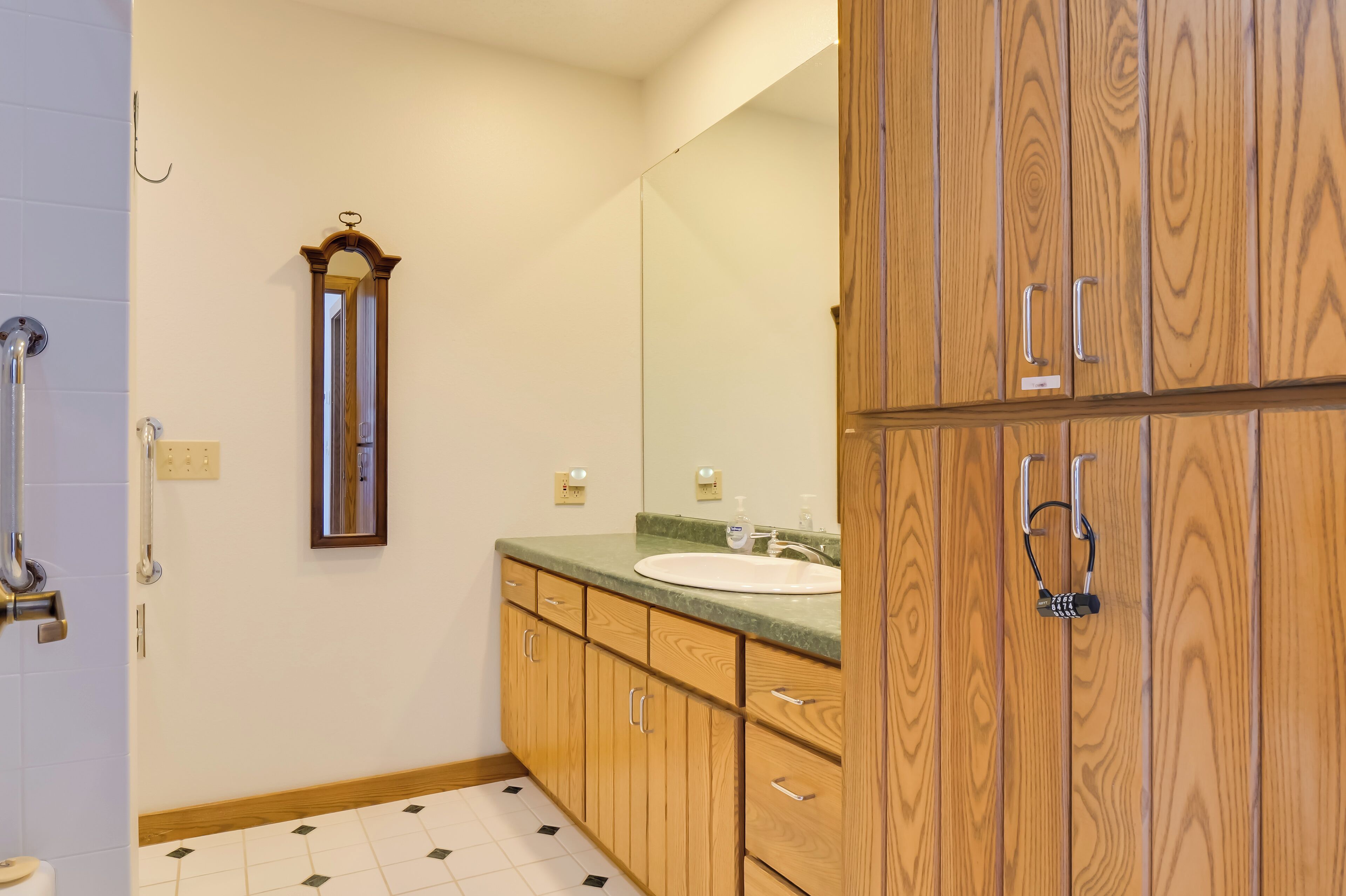 Une salle de bain avec des meubles en bois, un lavabo et un miroir.