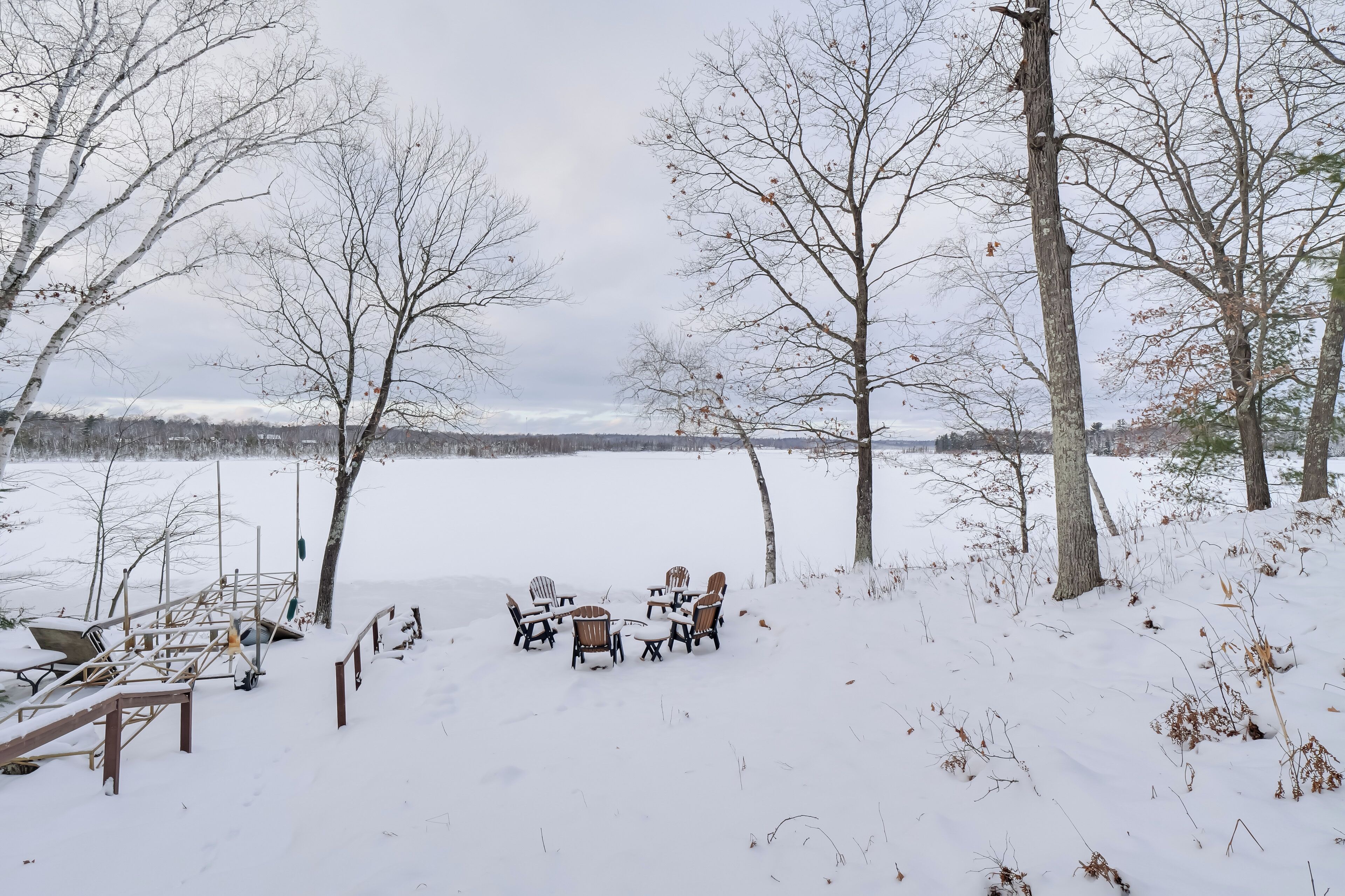 Un espacio al aire libre cubierto de nieve con una terraza de madera y sillas dispuestas para sentarse.