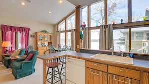 A kitchen with wooden cabinets, a dishwasher, and a large window. - Lake Access w/ Dock! Hayward Cabin Hideaway (Hayward)