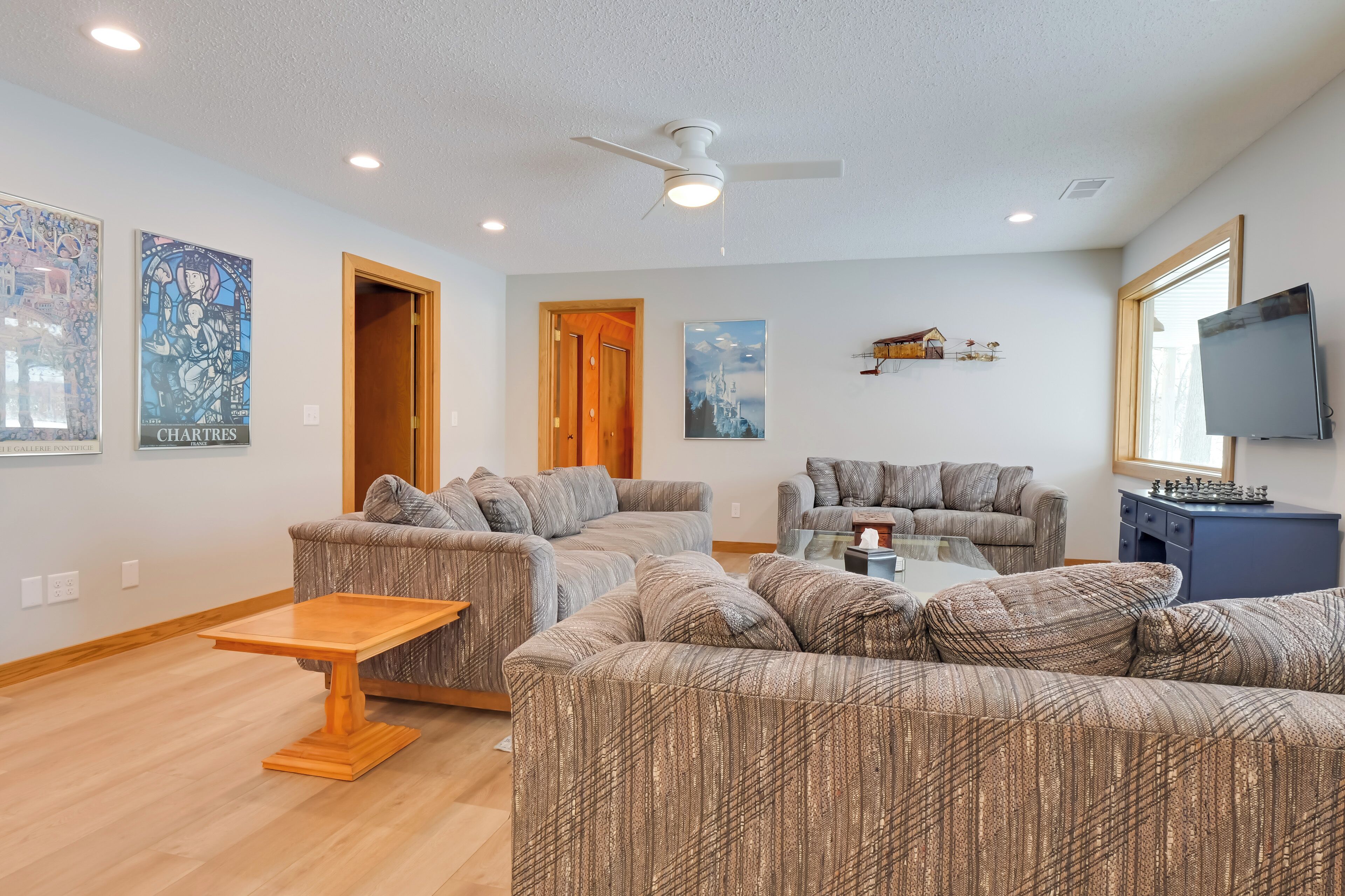A modern living room with sectional sofas, a wooden coffee table, and a ceiling fan.