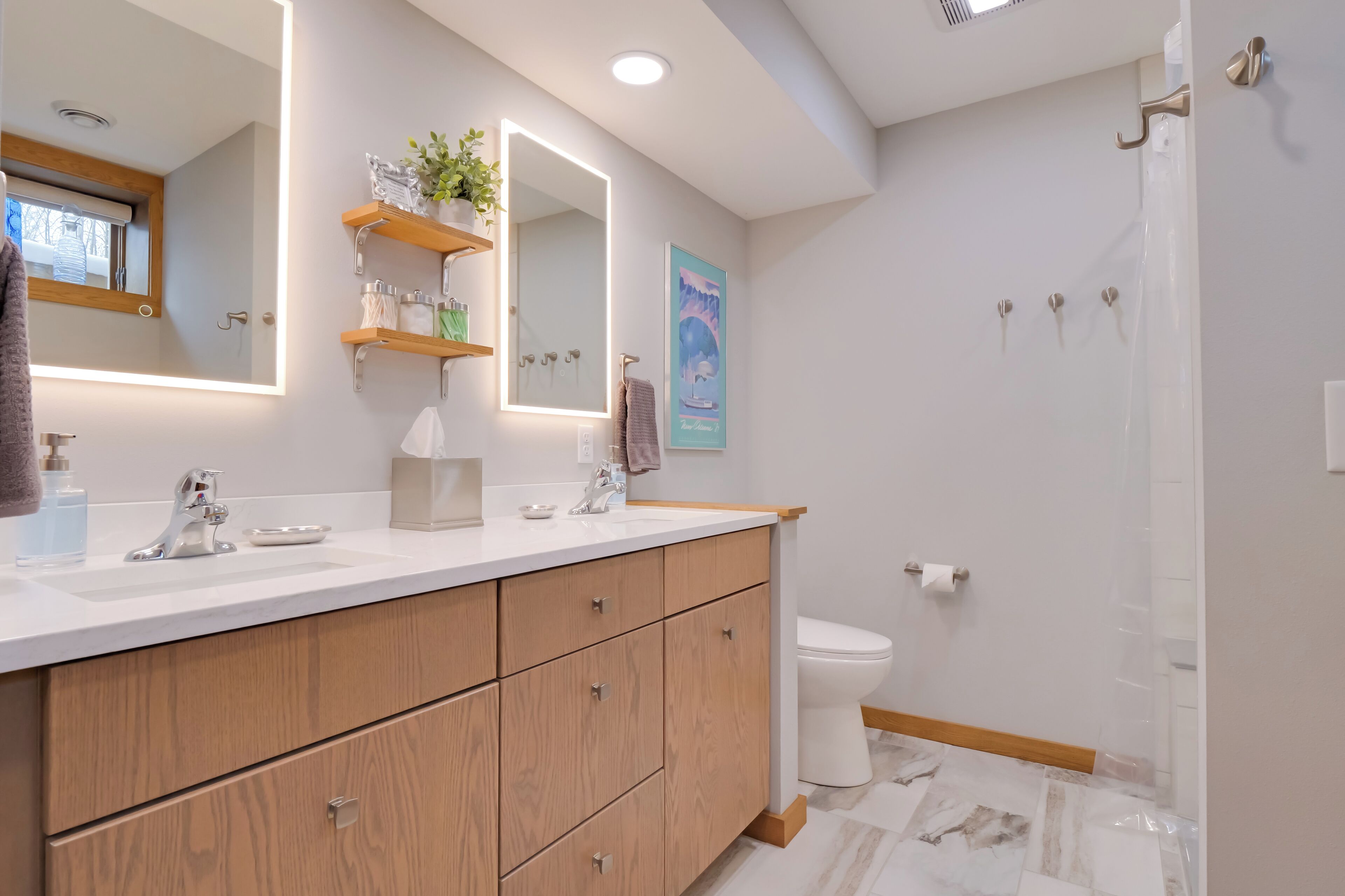 A modern bathroom with a wooden vanity, a large mirror, and a shower area.