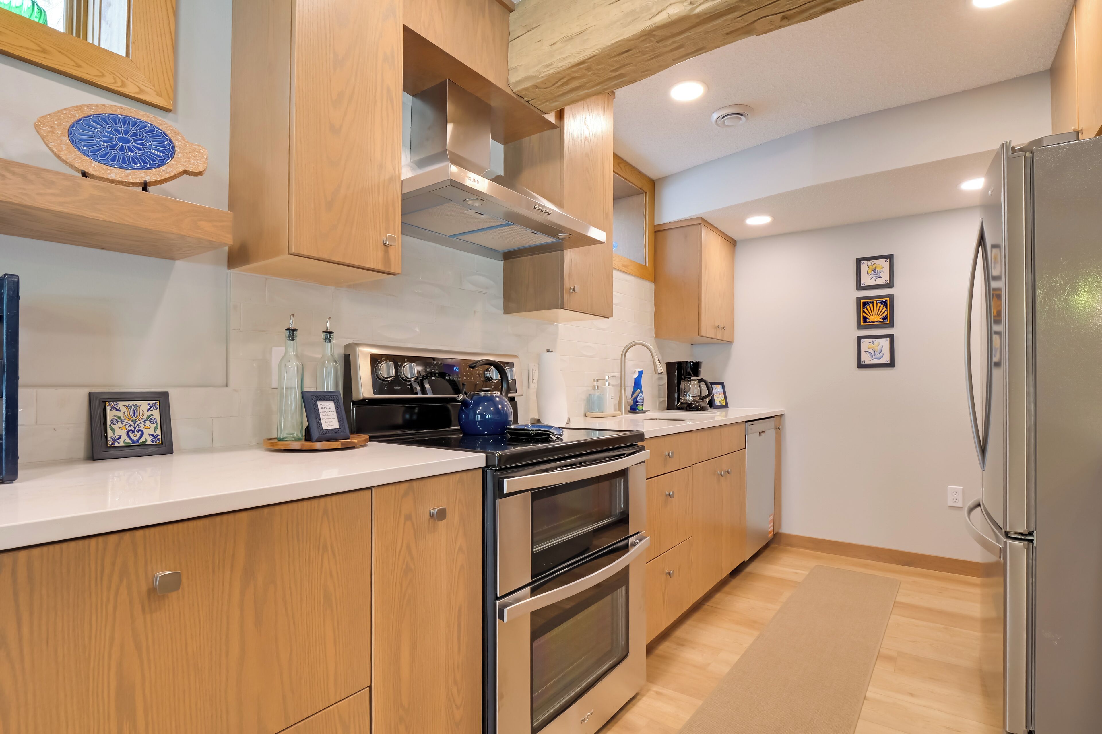 Une cuisine moderne avec des meubles en bois, des appareils en acier inoxydable et un plan de travail blanc.