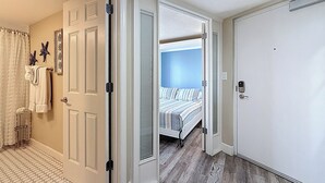 Een hotelkamer met een bed, een badkamer met douchegordijn en een deur met een handvat.