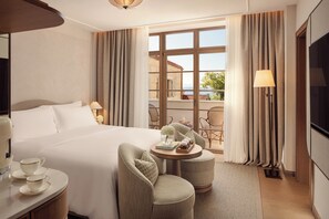 A hotel room with a large bed, a round table with chairs, a TV, and a view of the sea through large windows. - The Bristol Bol, New in 2027 (Bol)