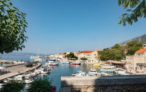A marina with boats docked, a stone wall, and buildings with red roofs. - The Bristol Bol, New in 2026 (Bol)