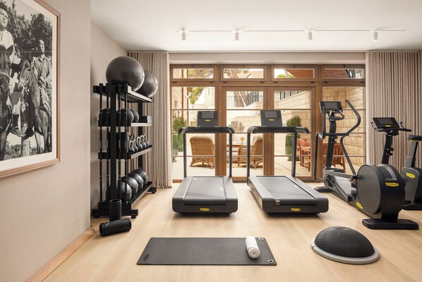 A gym with treadmills, a stationary bike, a rowing machine, and a wall-mounted weight rack. - The Bristol Bol, New in 2027 (Bol)