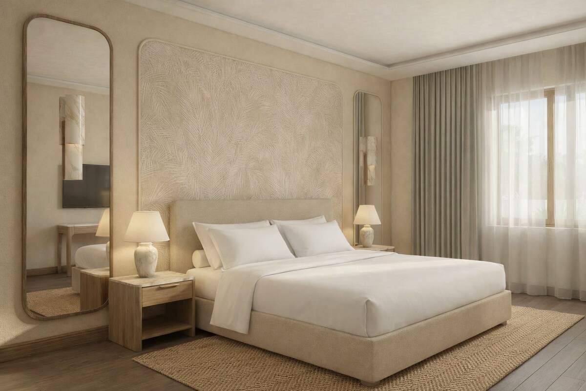 A modern hotel room with a large bed, two bedside tables with lamps, a large mirror, and a view of the outdoors through sheer curtains.