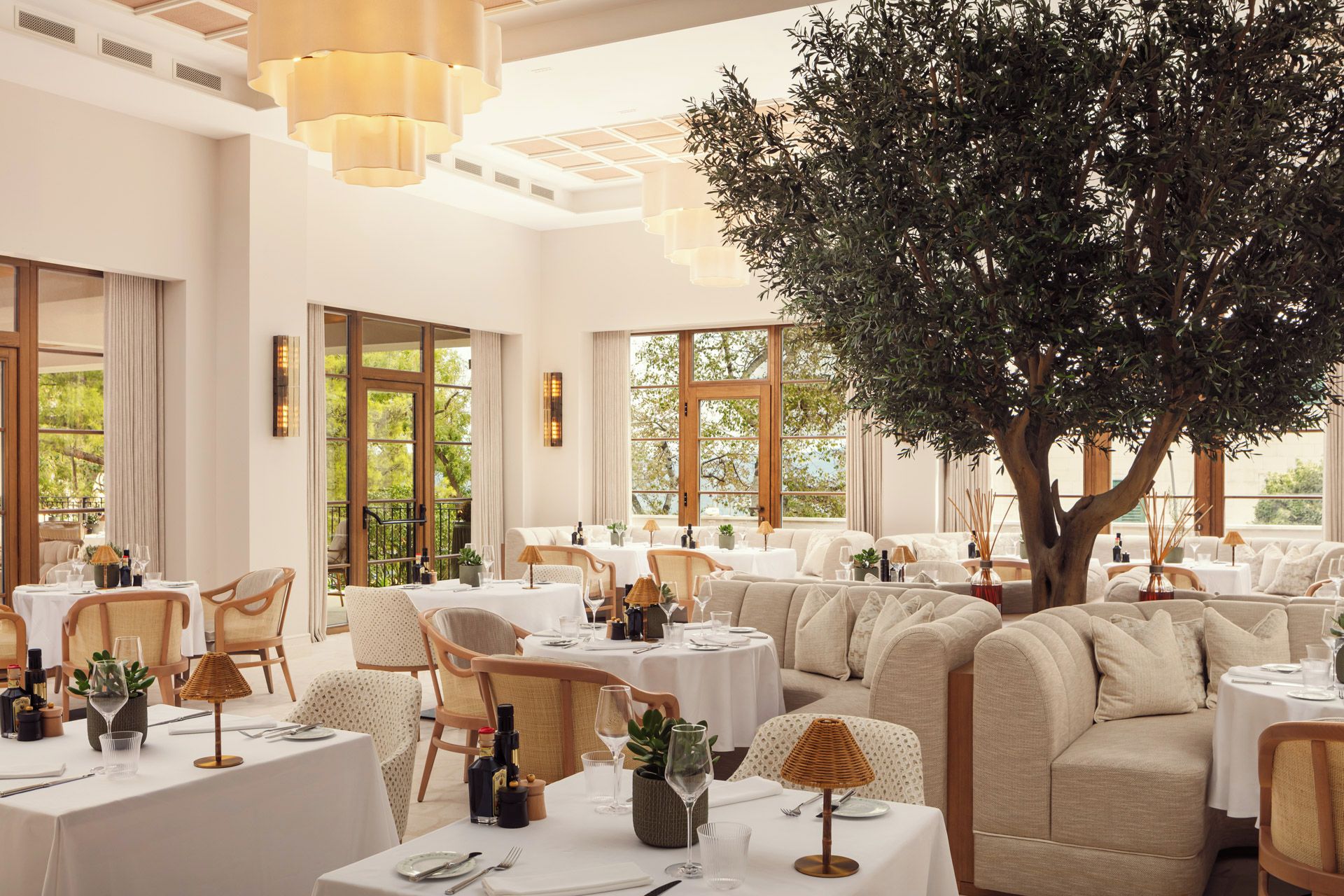 Un ristorante con tavoli rotondi, sedie e un grande albero al centro.