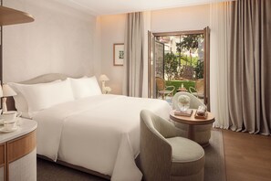 A hotel room with a bed, a sitting area with a chair and a small table, a lamp, and a view of the outdoors. - The Bristol Bol, New in 2026 (Bol)
