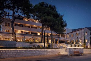 A multi-story hotel with a stone facade, outdoor seating, and a well-lit entrance. - The Bristol Bol, New in 2027 (Bol)