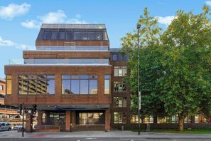 A multi-story building with a brick facade, large windows, and a flat roof. - Stylish Feltham Studio near Station & Shops (Vilnius)