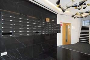 Eine moderne Lobby mit einer Wand aus schwarzem Marmor, einer Reihe von Briefkästen und einer Treppe.