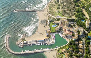 Luftaufnahme eines Küstenresorts mit einer Marina, Strand und Wohngebieten.