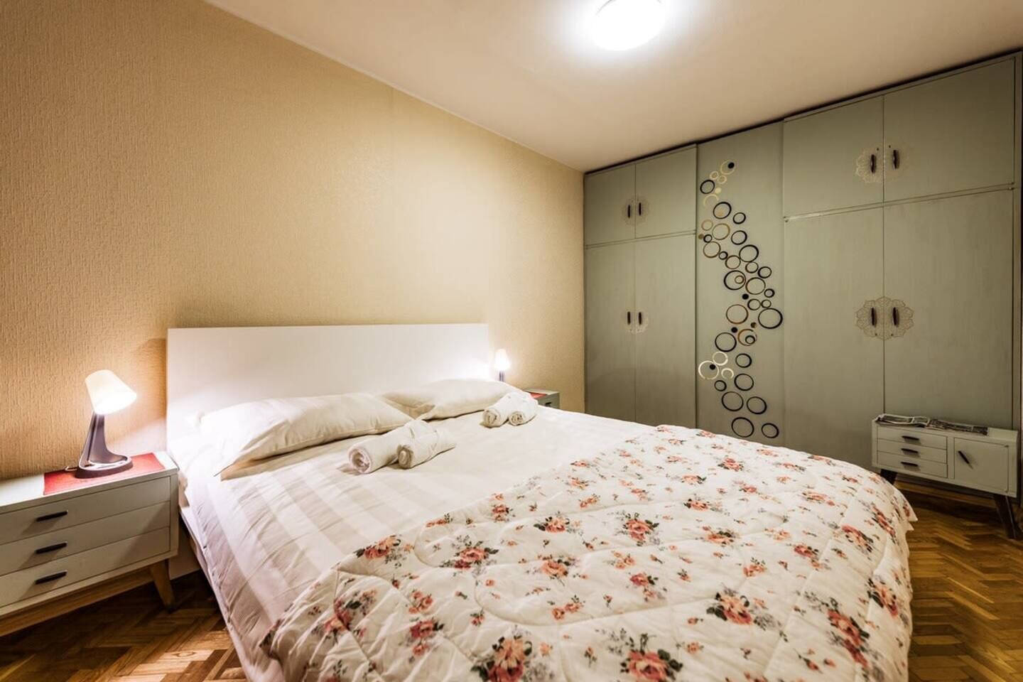 A bedroom with a bed, bedside tables, a wardrobe, and a lamp.