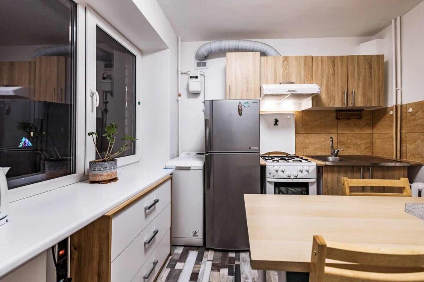 A compact kitchen with a refrigerator, stove, and wooden cabinets.