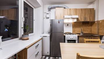 A compact kitchen with a refrigerator, stove, and wooden cabinets.