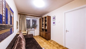 A living room with a sofa, a wooden cabinet, a window with curtains, and a door.