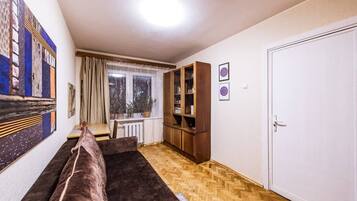 A living room with a sofa, a wooden cabinet, a window with curtains, and a door.