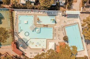 An aerial view of a swimming pool complex with multiple pools, sun loungers, and a tennis court. - The Charming Marina Village Tipo3-3 Bedroom Villa 6 Persons (Comacchio)