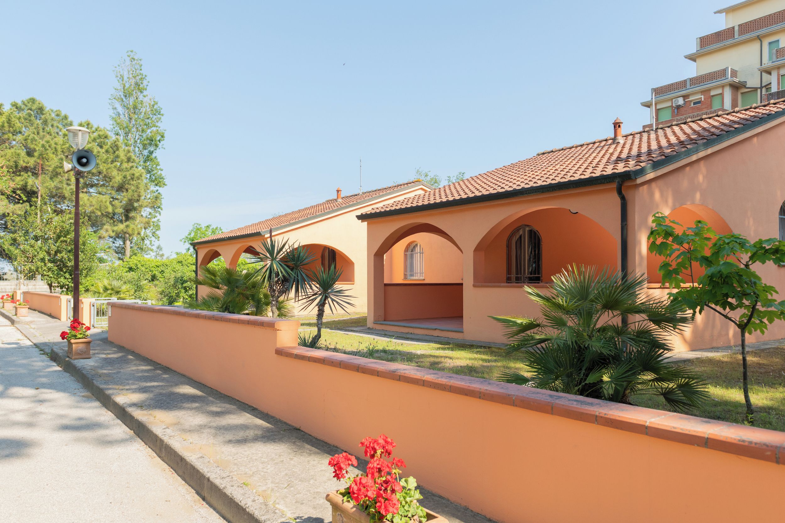 A building with a terracotta facade, arched windows, and a tiled roof.
