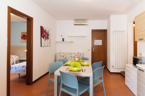 A dining area with a table set for four, blue chairs, a microwave, and a white cabinet. - The Charming Marina Village Tipo3-3 Bedroom Villa 6 Persons (Comacchio)