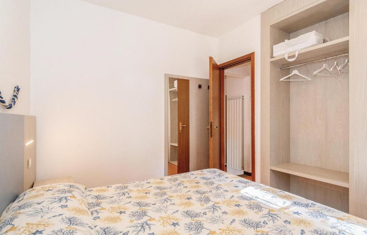 A bedroom with a bed, a wardrobe, and a door leading to another room.
