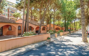 A row of orange buildings with arched windows and a paved street lined with trees. - The Charming Marina Village Tipo3-3 Bedroom Villa 6 Persons (Comacchio)