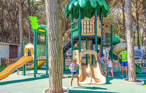 A playground with slides and climbing structures surrounded by trees. - The Charming Marina Village Tipo3-3 Bedroom Villa 6 Persons (Comacchio)