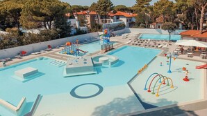 A swimming pool area with a water slide, lounge chairs, and a children's play area. - The Charming Marina Village Tipo3-3 Bedroom Villa 6 Persons (Comacchio)