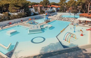 Ein Poolbereich mit Wasserrutsche, Liegestühlen und einem Spielbereich für Kinder.