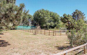 A fenced outdoor area with a grassy field and trees. - The Charming Marina Village Tipo3-3 Bedroom Villa 6 Persons (Comacchio)