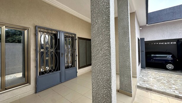 A spacious indoor area with a car parked in a covered garage. - Mariagletta Cozy Villa (Abomey-Calavi)