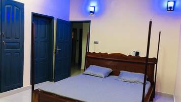 A bedroom with a four-poster bed, two wall-mounted lights, and a door leading to another room.