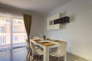 Un espace repas moderne avec une table en bois, des chaises blanches et une table avec un plateau en verre.