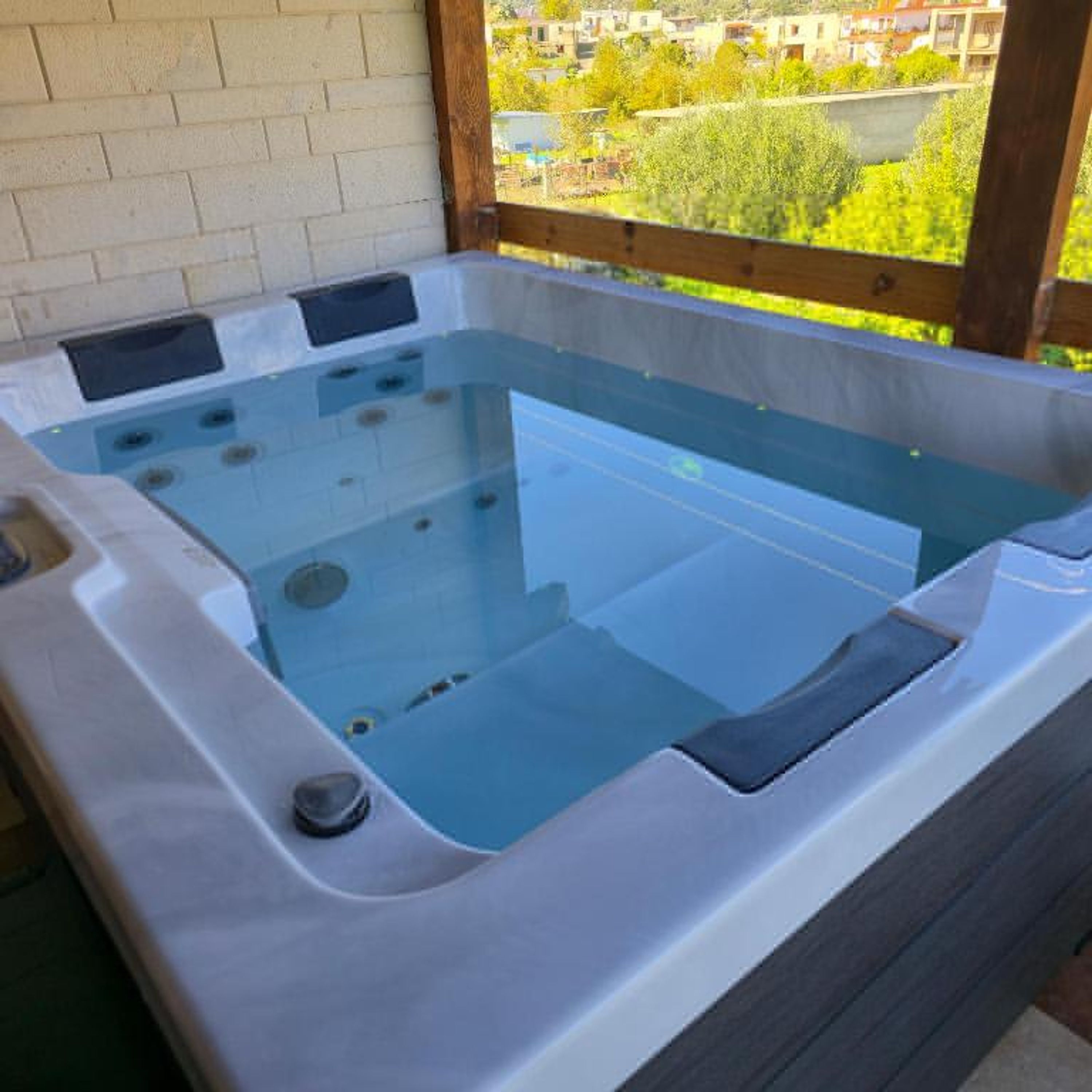 Una bañera de hidromasaje con terraza de madera y vista a una zona residencial.