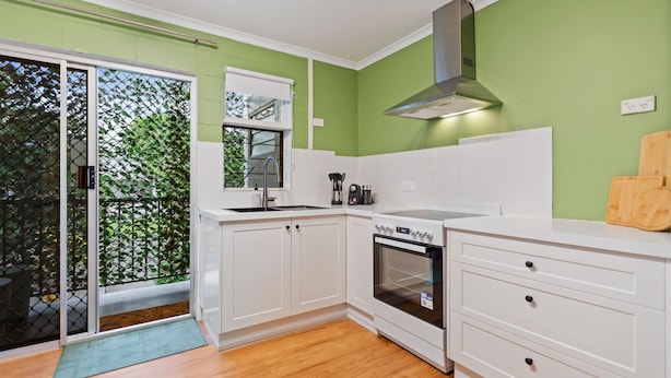 A kitchen with white cabinets, a stainless steel range hood, and a wooden countertop. - Botanica Studio Edge Hill (Cairns)