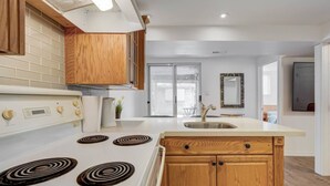 A modern kitchen with a white stove, wooden cabinets, and a large window. - Comfortable Whitby 2 Bedroom Lower Suite (Whitby)