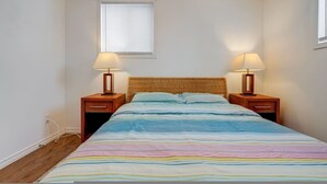 A bedroom with a bed, two bedside tables, a window, and a wall socket. - Comfortable Whitby 2 Bedroom Lower Suite (Whitby)