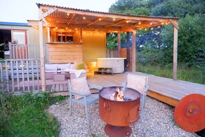 A cozy outdoor patio with a fire pit, wooden deck, and seating area. - Leworthy manor hideaways  (Holsworthy)