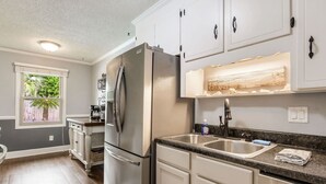 Une cuisine moderne avec des meubles blancs, des appareils en acier inoxydable et un plan de travail en granit.