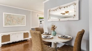 Un coin repas avec une table ronde, des chaises en osier, un miroir décoratif et une carte accrochée au mur.