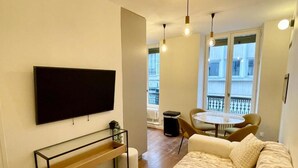 Un salon moderne doté d’un téléviseur à écran plat, d’un canapé, d’une table basse et de luminaires suspendus.