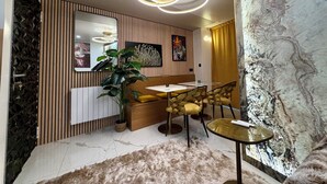 Un espace repas moderne avec un mur lambrissé en bois, un grand miroir, une plante en pot, un canapé et une table avec des chaises.