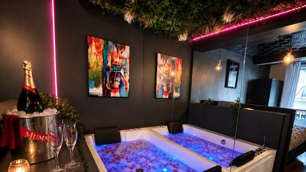 Une salle de bain moderne avec une grande baignoire, une bouteille de champagne et des verres posés sur un comptoir.