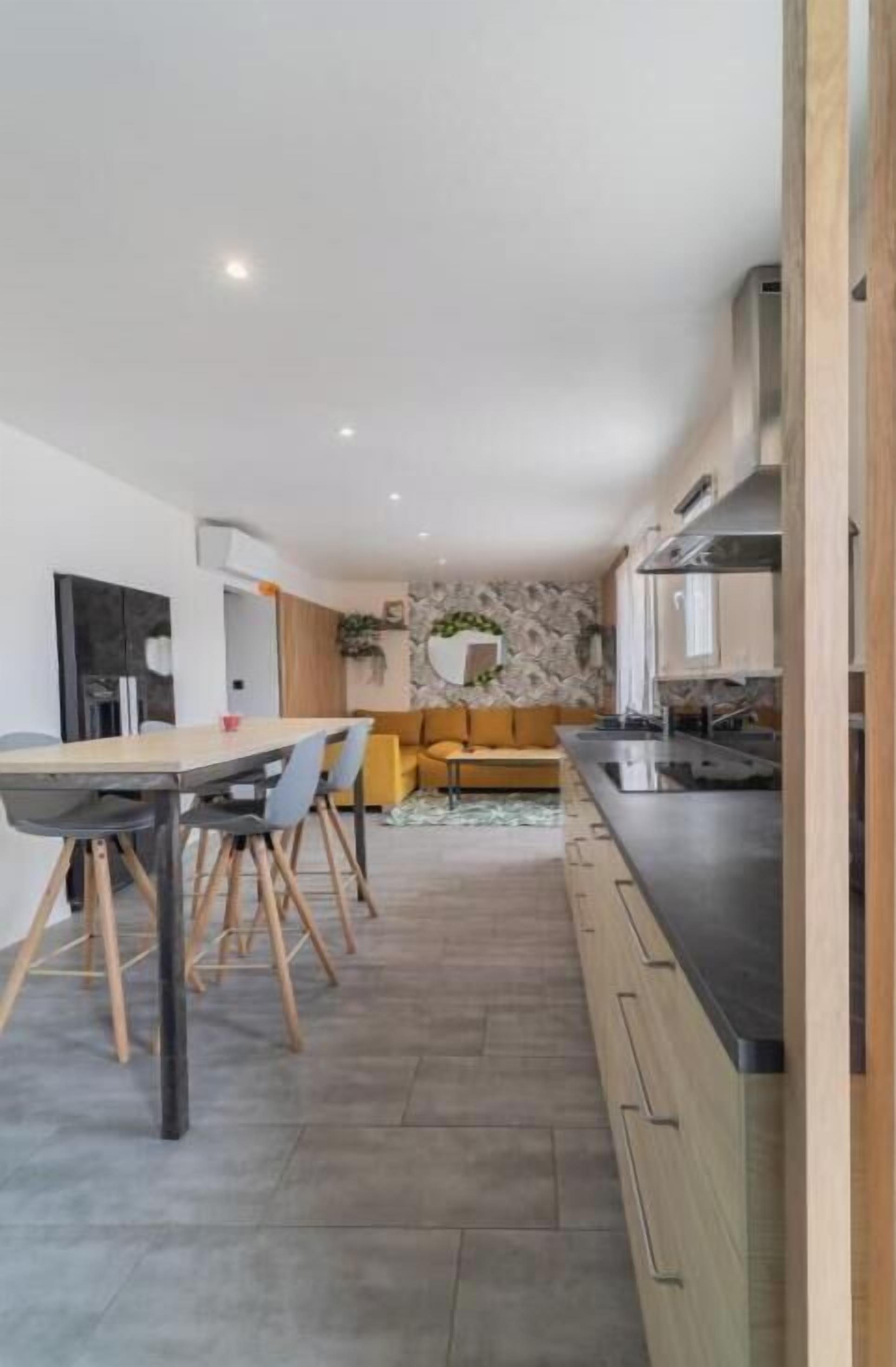 A modern kitchen with a dining area, built-in appliances, and a stone accent wall.