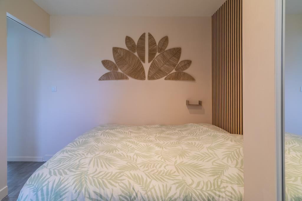 Un dormitorio con una cama, un adorno en la pared y un panel de madera vertical.