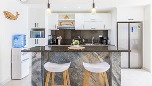Una cucina moderna con isola in marmo, mobili bianchi ed elettrodomestici in acciaio inossidabile.