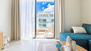 Un soggiorno moderno con un divano, un tavolino e vista su un balcone con mobili da esterno.