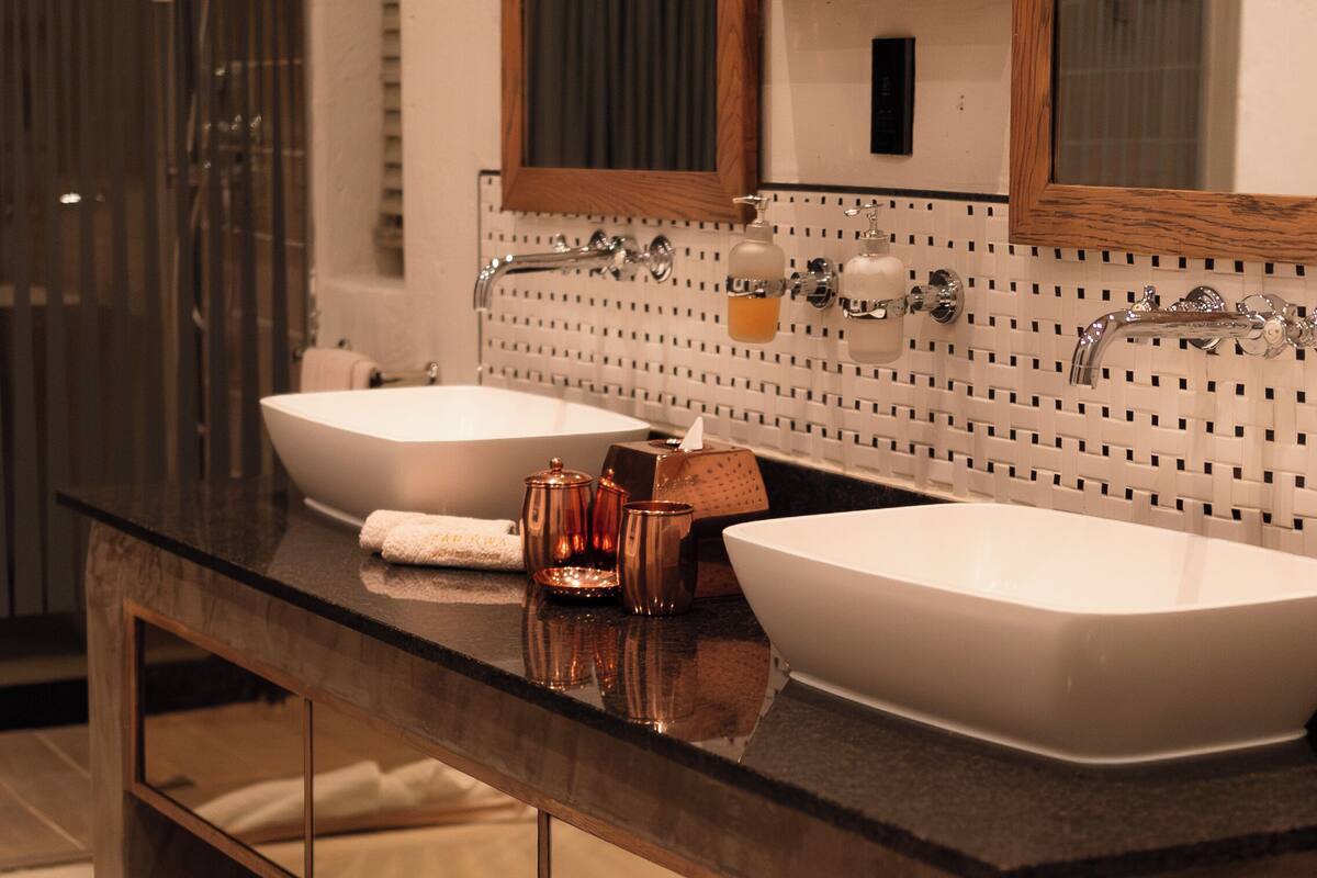 A modern bathroom with two large white sinks, a wooden vanity, and a large mirror above the sinks.